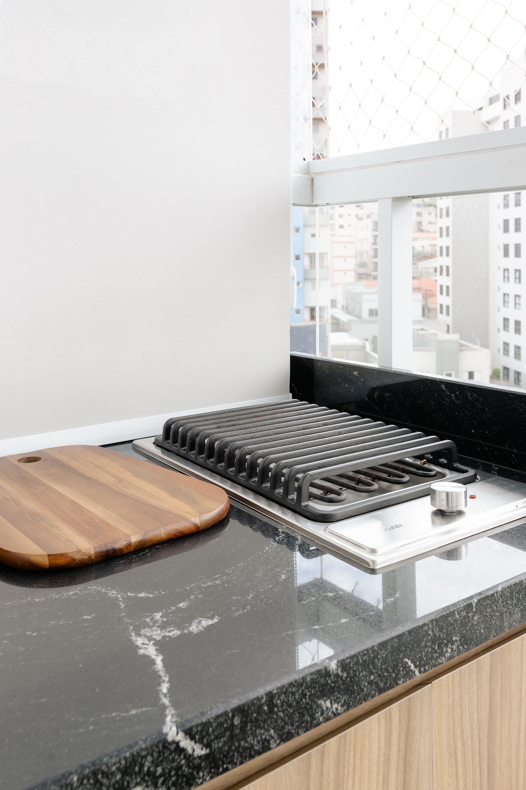 Cozinha com bancada funcional e banquetas pretas em projeto de interiores para apartamentos compactos